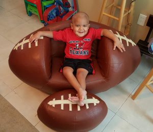 Gavin sitting in his football chair and Texan's shirt.